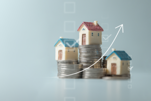 Miniatuurhuizen op stapels munten met stijgende grafiek die groei van vastgoedwaarde en inflatiebescherming illustreert.
